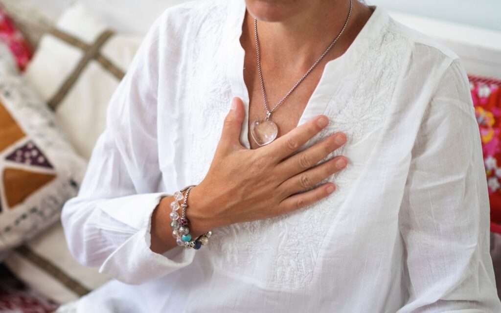 Frau legt die Hände auf ihre Brust – Symbol für innere Ruhe, Regulierung von Stress, Schlaf, Nervensystem und Trauma bei Hashimoto.
