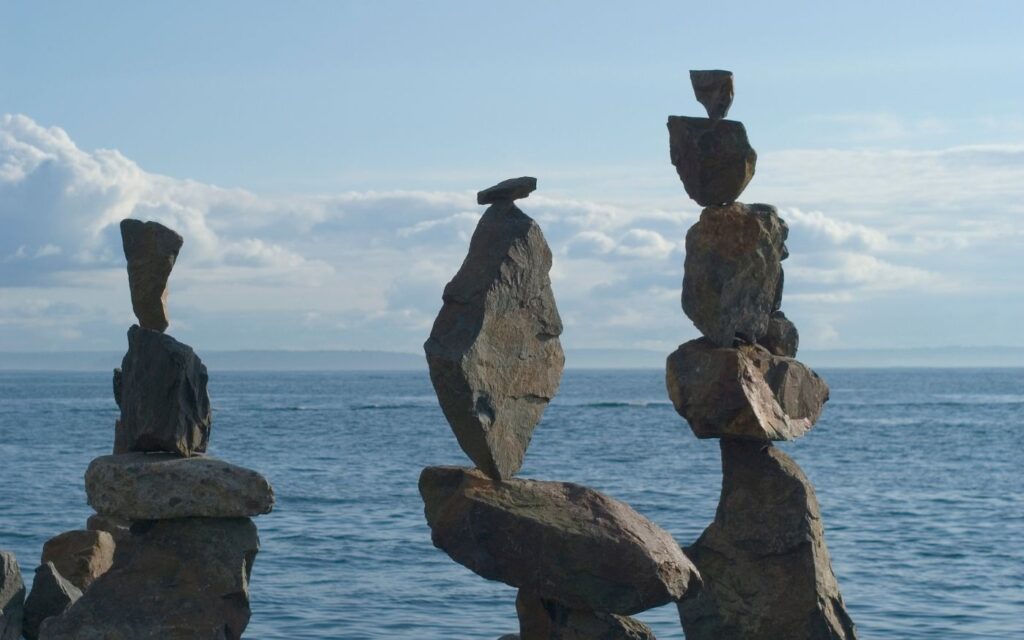 Gestapelte Steine am Wasser – Symbol für Balance und Regulation des Nervensystems trotz Stress und Trauma.