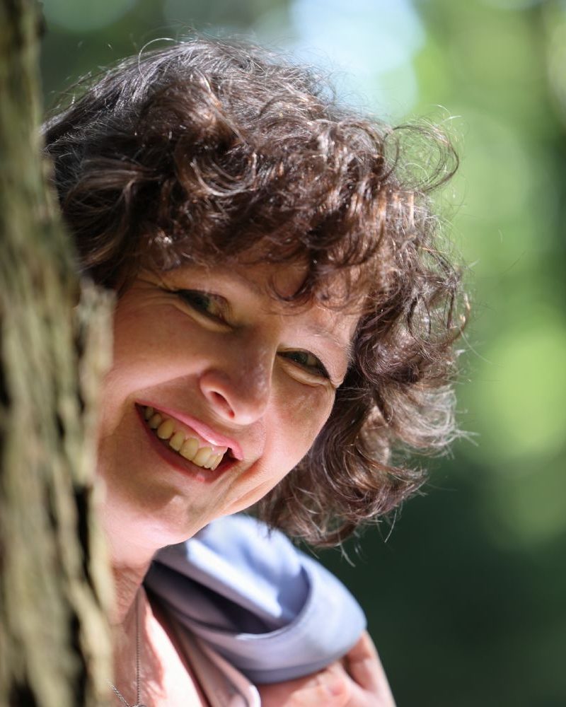 Manuela Glas lächelnd neben einem Baum - persönliche Vorstellung auf der Über-mich-Seite