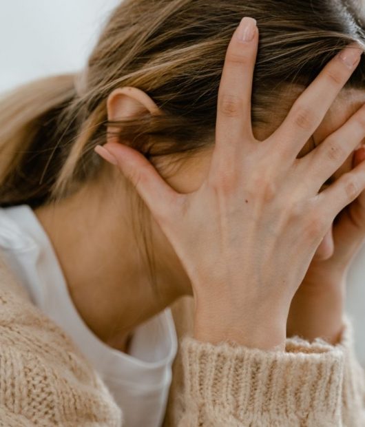 nervensystem-stress-trauma-ueberforderung-ueberlastung Frau mit Kopf in den Händen – Symbol für Stress, Überforderung und Trauma, die das Nervensystem aus dem Gleichgewicht bringen.